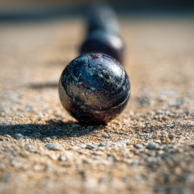 Hráči pétanque stoja v tieni, mäkké svetlo, letná atmosféra